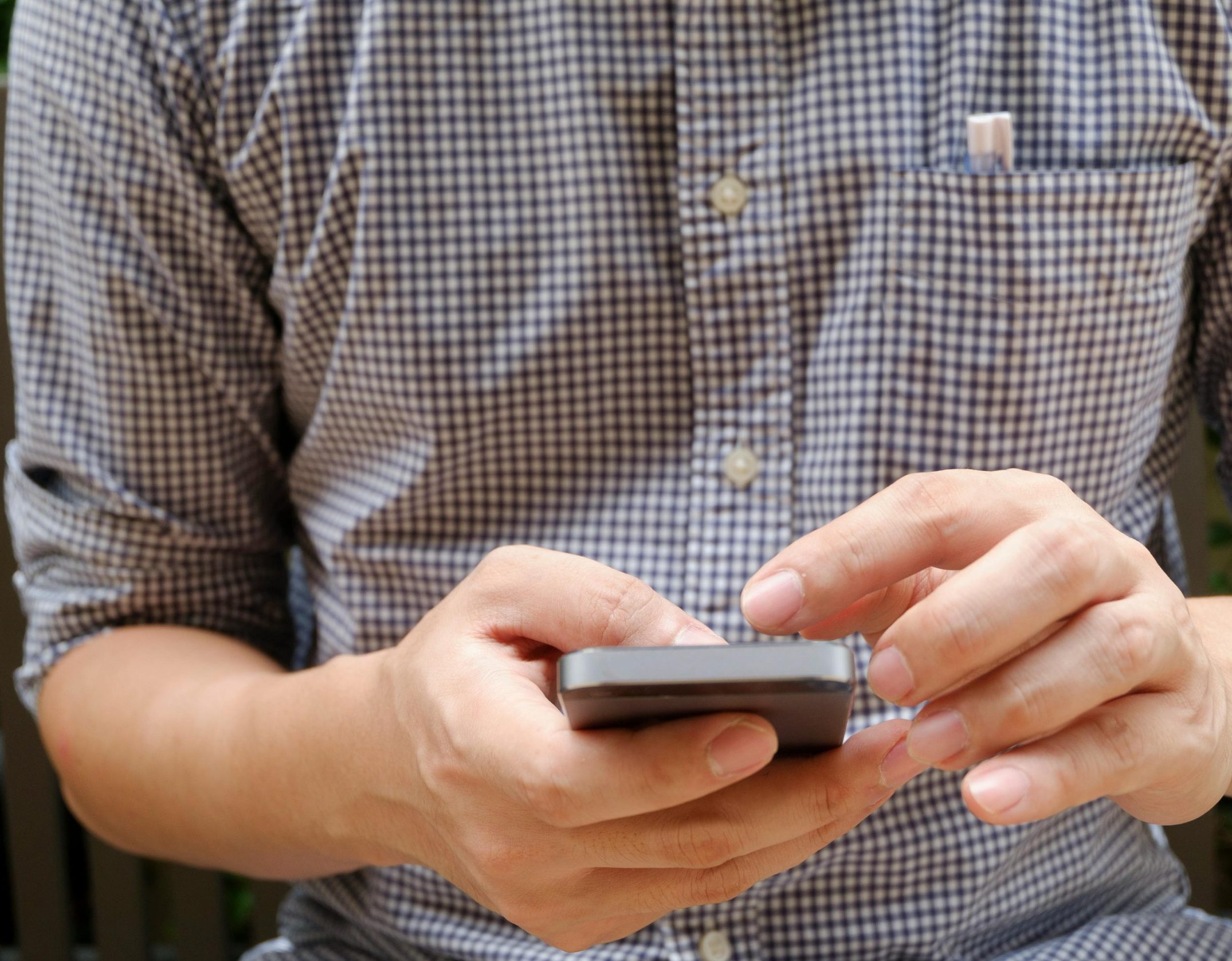 Close-up of a man using a smartphone, focusing on hands and modern technology.